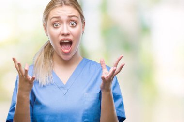 Üzerinde tıbbi üniforma giyen genç sarışın cerrah doktor kadın arka plan deli izole ve deli bağırarak ve agresif ifade ve silah kaldırdı bağırıyor. Hayal kırıklığı kavramı.