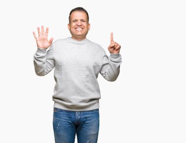 Gösterilen arka plan üzerinde spor kazak giyen orta yaş Arap adam izole ve parmakları ile işaret kendinden emin ve mutlu gülümseyerek süre 6 numara.