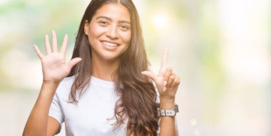 Genç güzel Arap kadın gösterilen ve parmakları ile işaret izole arka plan yüzünden kendinden emin ve mutlu gülümseyerek süre yedi numara.