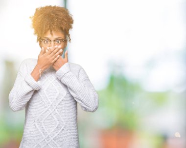 Üzerinde kış kazak giyen güzel genç Afro-Amerikan kadın arka plan ağız hata için elleriyle kapsayan şok izole. Gizli kavramı.