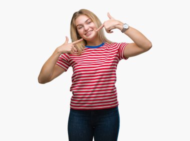 Kendinden emin gösterilen ve işaret parmakları diş ve ağız ile gülümseyen izole arka plan üzerinde beyaz kadın. Sağlık kavramı.