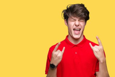 Deli ifade rock simge elle yapıyor ile bağırarak izole arka plan üzerinde kırmızı t-shirt giyen genç yakışıklı adam. Müzik yıldızı. Ağır kavramı.