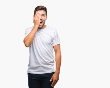 El yüz ve sürpriz duygu kendinden emin gülümseme ile tek gözüyle kapsayan izole arka plan üzerinde genç yakışıklı adam.