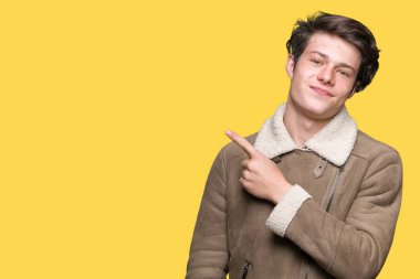 Genç yakışıklı adam giyen kış ceket izole üzerinden reklam, ciddi ve sakin yüz gösterilen yan el parmak ile işaret arka plan