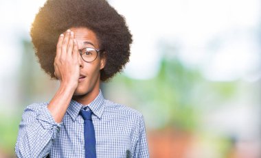 Genç Afro-Amerikalı iş adamı afro saçlı gözlüklü yüz ve sürpriz duygu kendinden emin gülümseme ile el ile bir göz kapsayan.