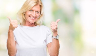 Orta yaş sarışın kadın el ile pozitif jest yapıyor izole arka plan başarı işareti yüzünden başparmak gülümseyen ve mutlu. Neşeli bir ifadeyle, kazanan jest kameraya bakıyor.