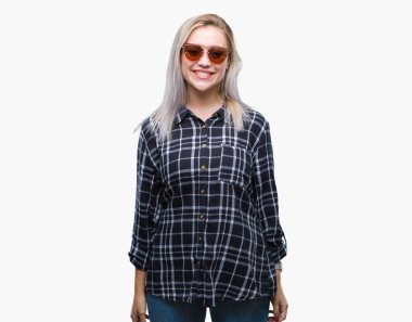 Sarışın genç kadın yüzünde mutlu ve güzel bir gülümseme ile izole arka plan üzerinde güneş gözlüğü takıyor. Şanslı kişi.