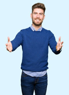 Genç yakışıklı bussines adam sarılmak için kollarını açarak gülümseyen kamera bakıyor. Neşeli ifade kucaklayan mutluluk.