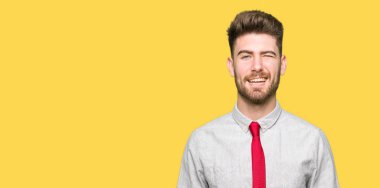 Genç yakışıklı iş adamı seksi bir ifadeyle, neşeli ve mutlu yüzünü kameraya bakarak göz kırpıyor.