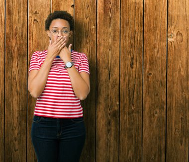 Güzel genç Afro-Amerikan kadın üzerinde gözlük takan arka plan ağız hata için elleriyle kapsayan şok izole. Gizli kavramı.