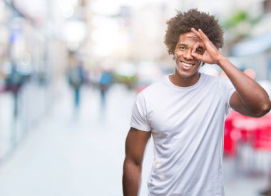 Afro Amerikalı adam gülümsüyor, parmakları ile mutlu yüz üzerinden seyir göz el ile ok jest yapıyor izole arka plan üzerinde.