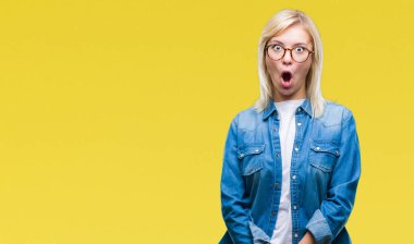 Korkuyor ve şok sürpriz ifade, korku ve heyecan yüz ile izole arka plan üzerinde gözlük takan genç güzel sarışın kadın.
