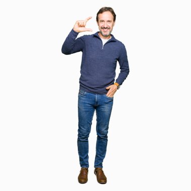 Bir kazak gülümseyen ve süre seyir ve kamera boyutu işaret parmaklarıyla yapıyor el ile kendine güvenen el hareketi giyen orta yaş yakışıklı adam. Ölçü kavramı.