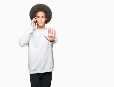Açık eliyle dur işareti ile ciddi ve kendine güvenen ifade, savunma jest yapıyor smartphone üzerinde konuşurken afro saçlı genç Afro-Amerikan adam