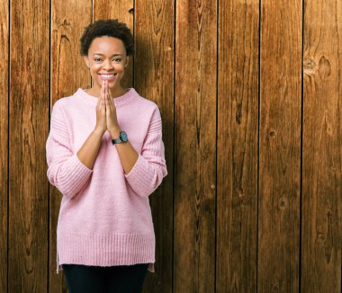 Birlikte emin gülümseyen bağışlanmak ellerle dua izole arka plan güzel genç Afro-Amerikan kadın.