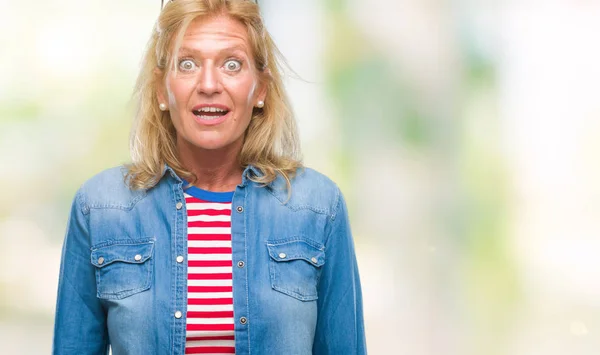Middle age blonde woman over isolated background afraid and shocked with surprise expression, fear and excited face.