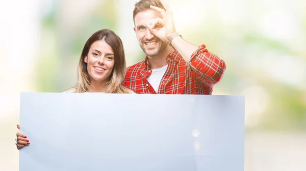 Casal Jovem Juntos Segurando Banner Branco Sobre Fundo Isolado Com — Fotografia de Stock