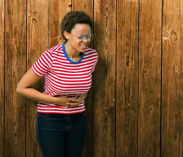 美丽的年轻非洲裔美国妇女戴眼镜在孤立的背景与手在胃 因为恶心 痛苦的疾病感觉不舒服 Ache — 图库照片