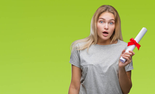 Young caucasian woman holding degree over isolated background scared in shock with a surprise face, afraid and excited with fear expression