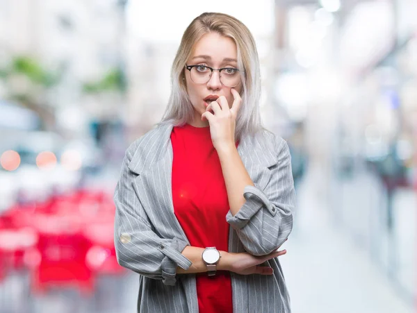 年轻的金发女商人穿着时尚夹克在孤立的背景下看紧张和紧张与手在嘴咬指甲 焦虑问题 — 图库照片