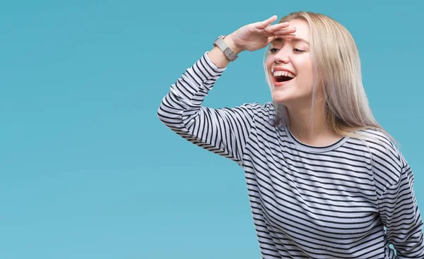 Young blonde woman over isolated background very happy and smiling looking far away with hand over head. Searching concept.