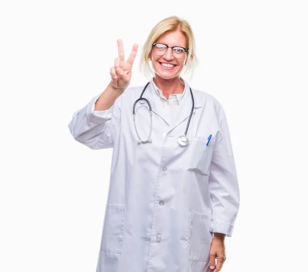 中年金发医生妇女在孤立的背景显示和指向与手指第二 微笑自信和快乐 — 图库照片