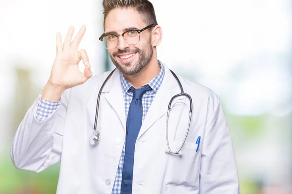 英俊的年轻医生人在被隔绝的背景微笑的正面做确定的标志用手和手指 成功的表达 — 图库照片