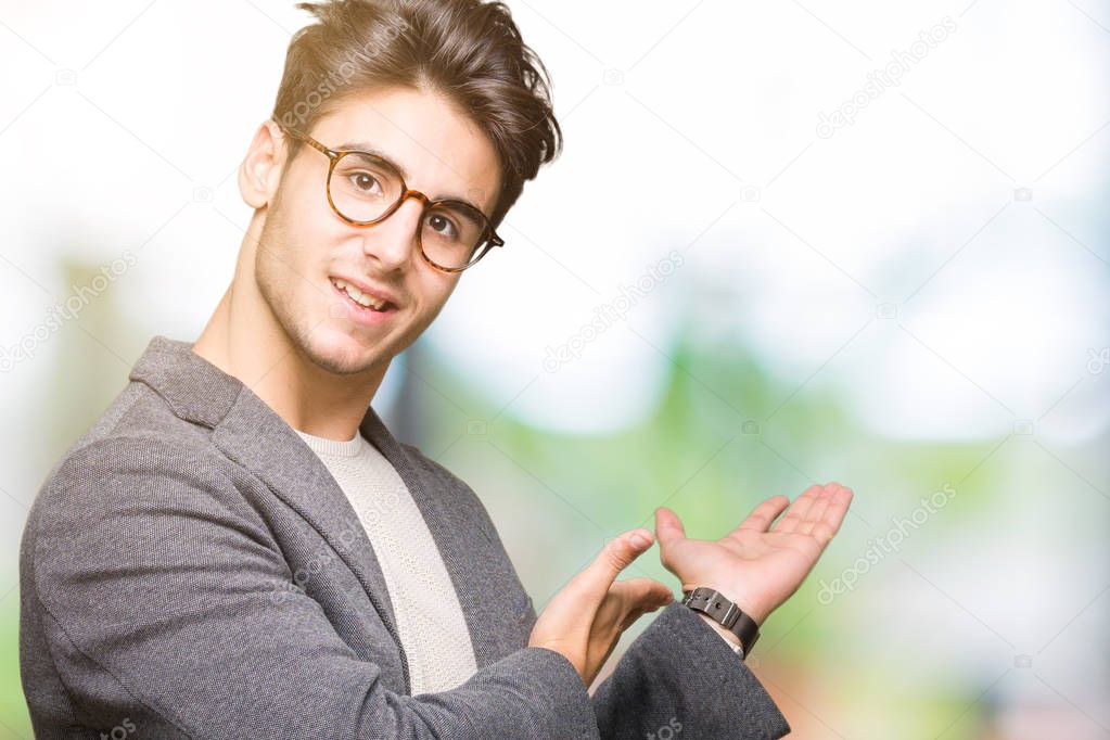 Young business man wearing glasses over isolated background Inviting to enter smiling natural with open hand