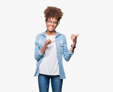 Güzel genç Afro-Amerikan kadın üzerinde gözlük takan izole arka plan emin gülümseyen arkasından el ve kadar başparmak ile işaret