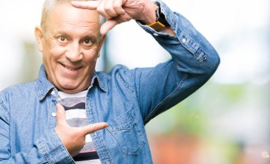 Denim ceket elle yapma çerçeve ve parmakları ile mutlu yüz gülümseyen yakışıklı komuta sizde. Yaratıcılık ve Fotoğrafçılık kavramı.