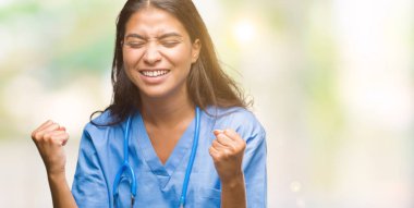 Gülümseyen ve başarı için çığlık genç Arap Doktor cerrah kadın izole arka plan çok mutlu ve heyecanlı kaldırdı, silah ile kazanan jest yapıyor. Kutlama kavramı.