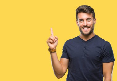 Kameraya bakarak yan el ve parmak ile işaret eden genç yakışıklı adam yüzünde kocaman bir gülümseme ile izole arka plan üzerinde.