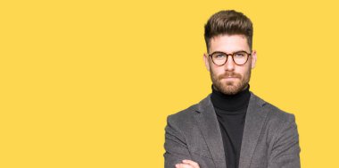 Yüz çapraz kolları üzerinde gözlük şüpheci ve sinir, onaylamayan ifade giyen genç yakışıklı iş adam. Negatif kişi.