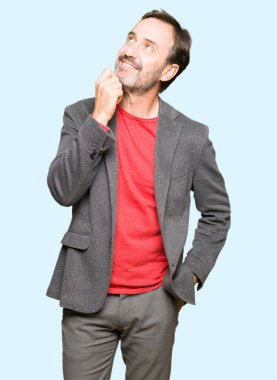 Çene düşünme hakkında soru, dalgın ifade üzerine el ile orta yaş yakışıklı iş adamı. Düşünceli yüzüyle gülümsüyor. Şüphe kavramı.