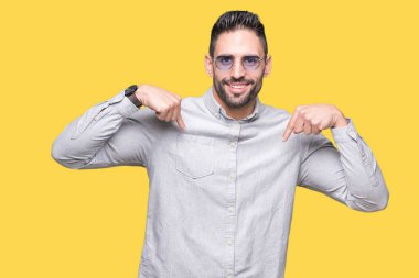 Yakışıklı delikanlı yüzünde gülümseme ile kendinden emin görünüyorsun, kendini gururlu ve mutlu parmakları ile işaret izole arka plan üzerinde güneş gözlüğü takıyor.