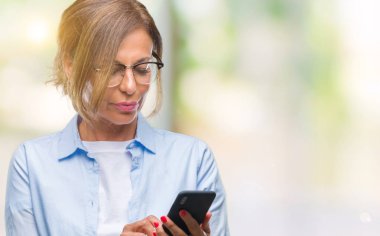 Orta yaş kadın kıdemli manifatura acımak yüz ciddi düşünüyorum üstünde kendine güvenen bir ifade ile izole arka plan üzerinde Smartphone kullanarak ileti gönderme