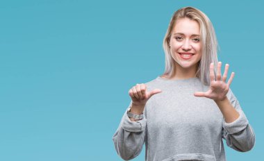 Sarışın genç kadın gösterilen ve parmakları ile işaret izole arka plan üzerinde kendinden emin ve mutlu gülümseyerek süre 6 numara.