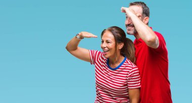 Orta yaş İspanyol çift izole arka plan çok mutlu ve gülümseyen uzakta ile seyir üzerinde aşık over head ver. Arama kavramı.