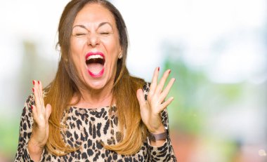 Güzel orta yaş kadın giyiyor leopar hayvan kızgın ve çığlık kaldırdı ve kapalı gözleri heyecanlı silah ile başarı için deli kutluyor elbise yazdırın. Kazanan kavramı