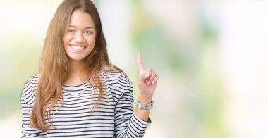 Ve parmak gülümseyen süre bir numara ile kendinden emin ve mutlu yukarıyı gösteren izole arka plan üzerinde çizgili süveter giyen genç güzel esmer kadın.