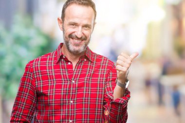 Orta yaş ağarmış komuta sizde seyir ve başparmak yanında yukarıyı mutlu yüz ile gülümseyen izole arka plan üzerinde.