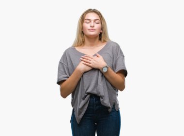 Eller genç beyaz kadın ile gülümseyen izole arka plan üzerinde kapalı gözler ve yüzünde minnettar jest ile göğüs üzerinde. Sağlık kavramı.