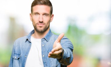 Kot giyen sakal ve mavi gözlü yakışıklı adamla tebrik ve davet edici olarak gülümseyen dostu sunan karşılıklı ceket. Başarılı iş.