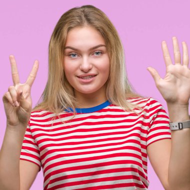 Gösterilen ve parmakları ile işaret izole arka plan üzerinde beyaz kadın kendinden emin ve mutlu gülümseyerek süre yedi numara.