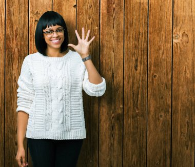 Güzel genç Afro-Amerikan kadın gözlük gösterilen ve parmakları ile işaret izole arka plan üzerinde kendinden emin ve mutlu gülümseyerek süre 5 numara.