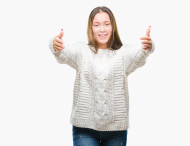 Sarılmak için kollarını açarak gülümseyerek kameraya bakarak izole arka plan üzerinde kış kazak giyen genç güzel beyaz kadın. Neşeli ifade kucaklayan mutluluk.