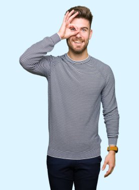 Gülümseyen, parmakları ile mutlu yüz üzerinden seyir göz el ile ok jest yapıyor çizgili süveter giyen genç yakışıklı adam.