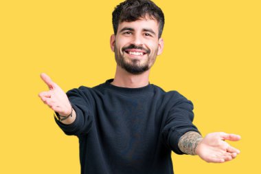 Yakışıklı delikanlı sarılmak için kollarını açarak gülümseyerek kameraya bakarak izole arka plan üzerinde. Neşeli ifade kucaklayan mutluluk.