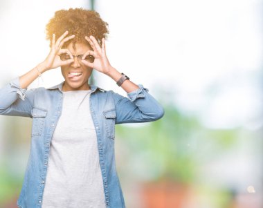 Dilini, parmaklarının arasından baktığını yapışmasını dürbün gibi ok jest yapıyor izole arka plan üzerinde gözlük güzel genç Afro-Amerikan kadın. Deli ifade.