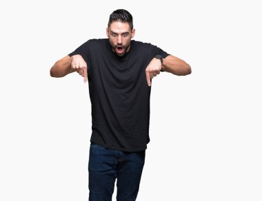 İzole genç yakışıklı adam arka plan işaretleme aşağı reklam, sürpriz yüz ve açık ağız gösterilen parmakları ile